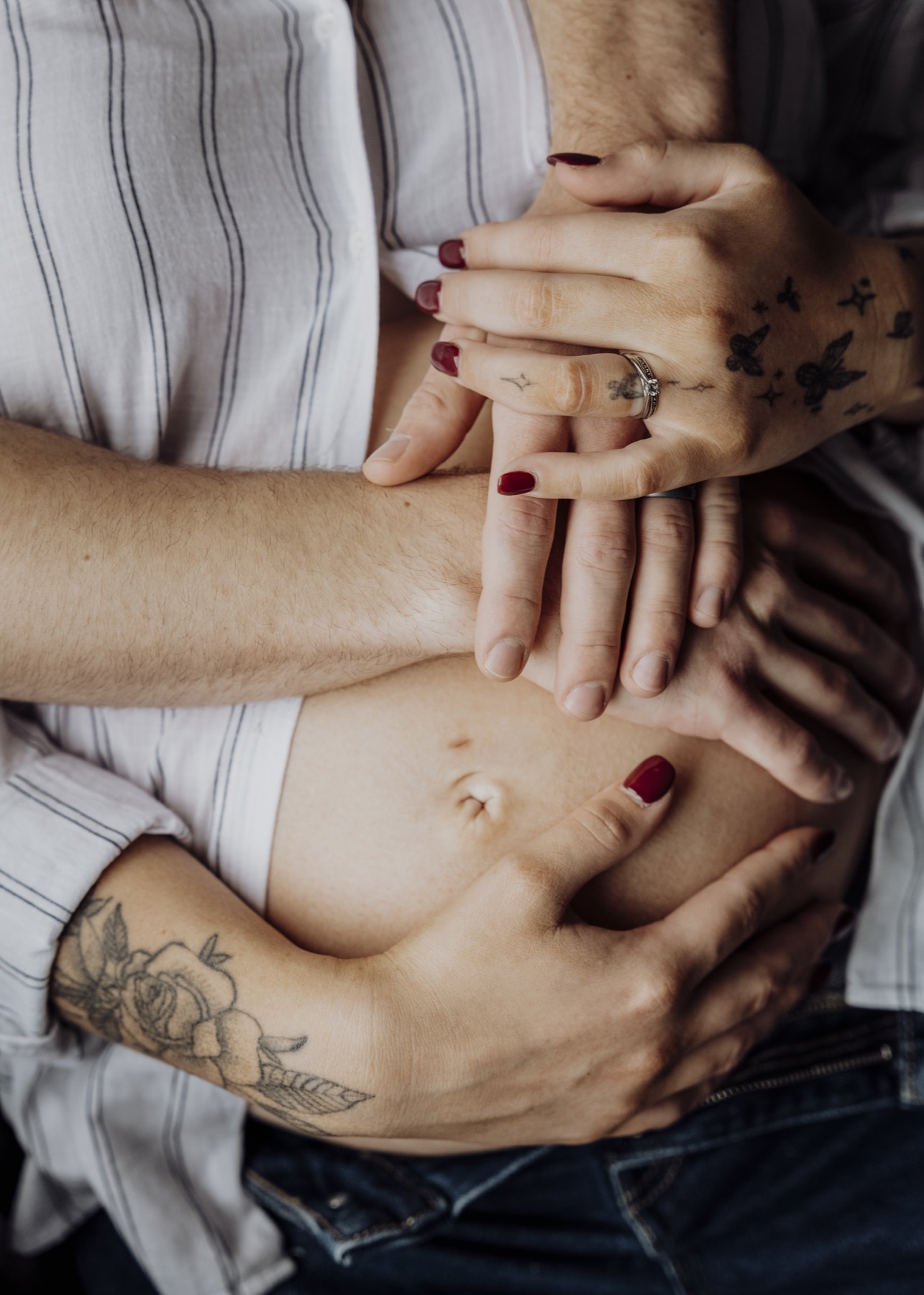 Expectant parents resting their hands together around a baby bump