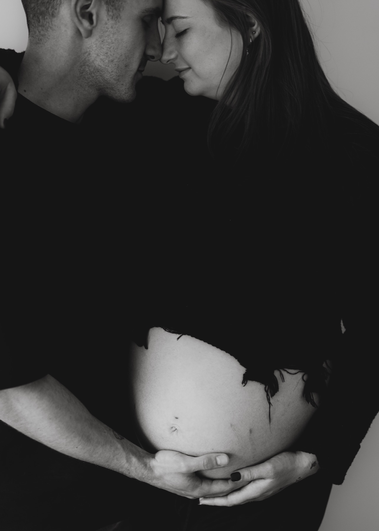 Black and white maternity portrait of a couple touching foreheads