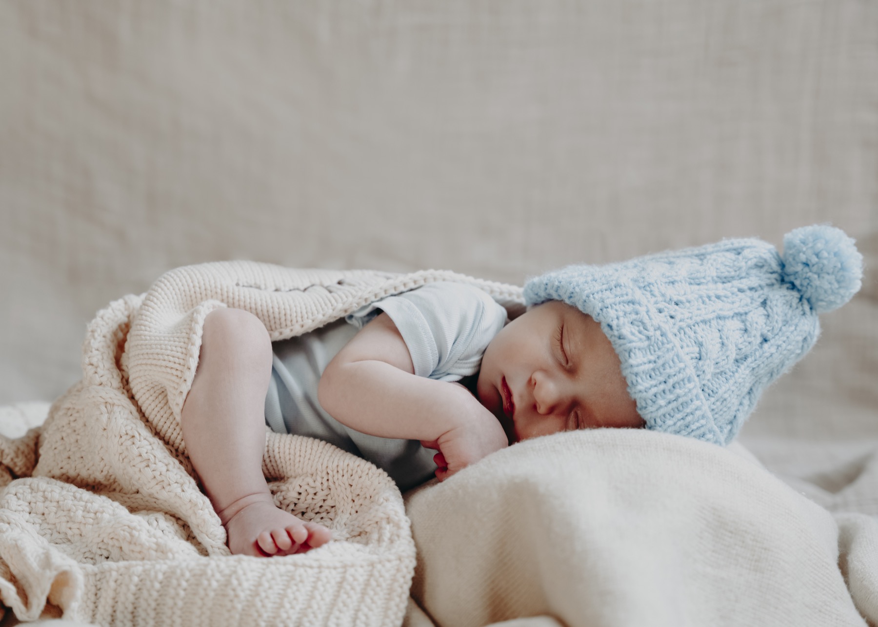 Sleeping newborn in a pale blue knitted hat