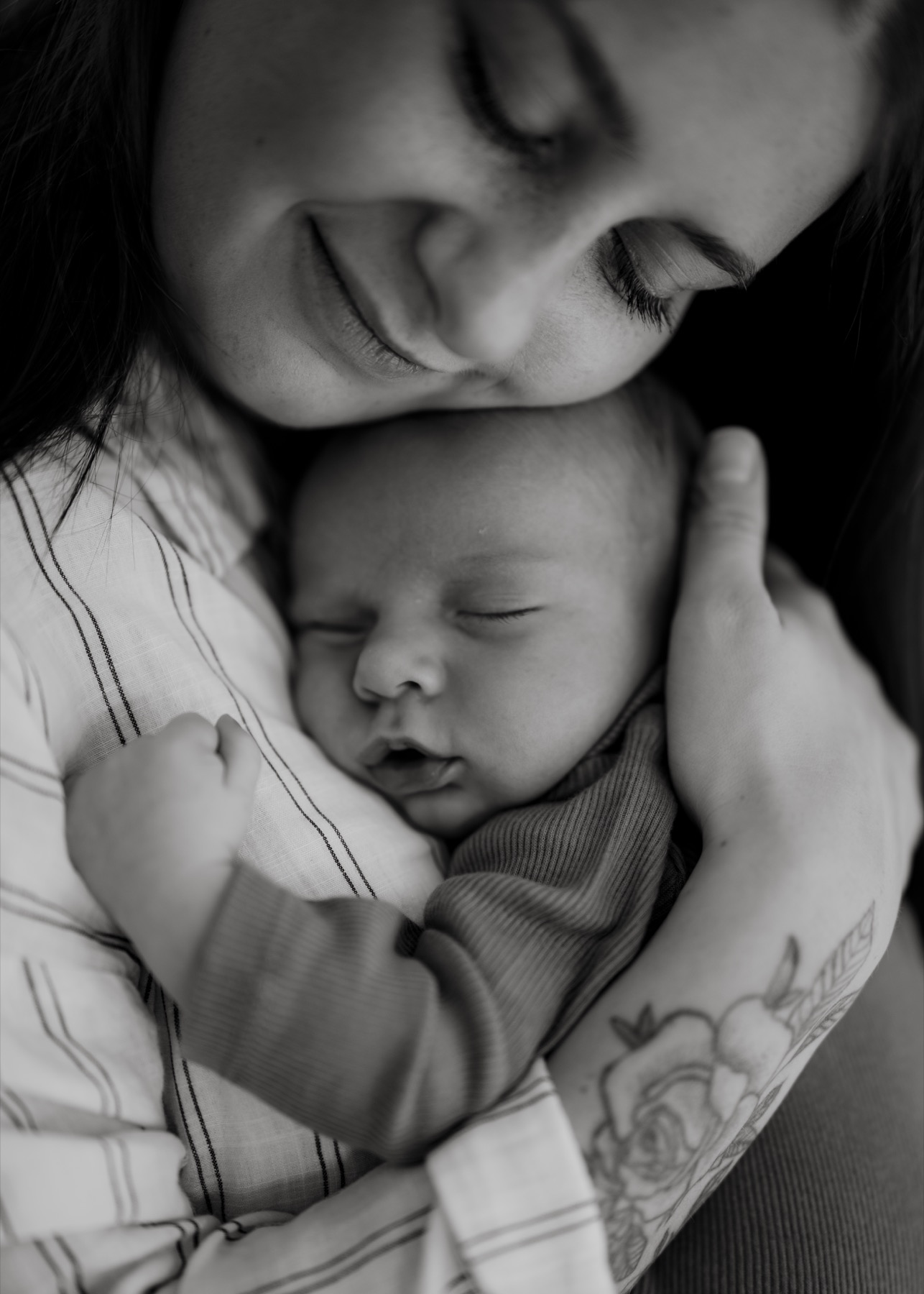 Black and white portrait of a mother cuddling her sleeping newborn