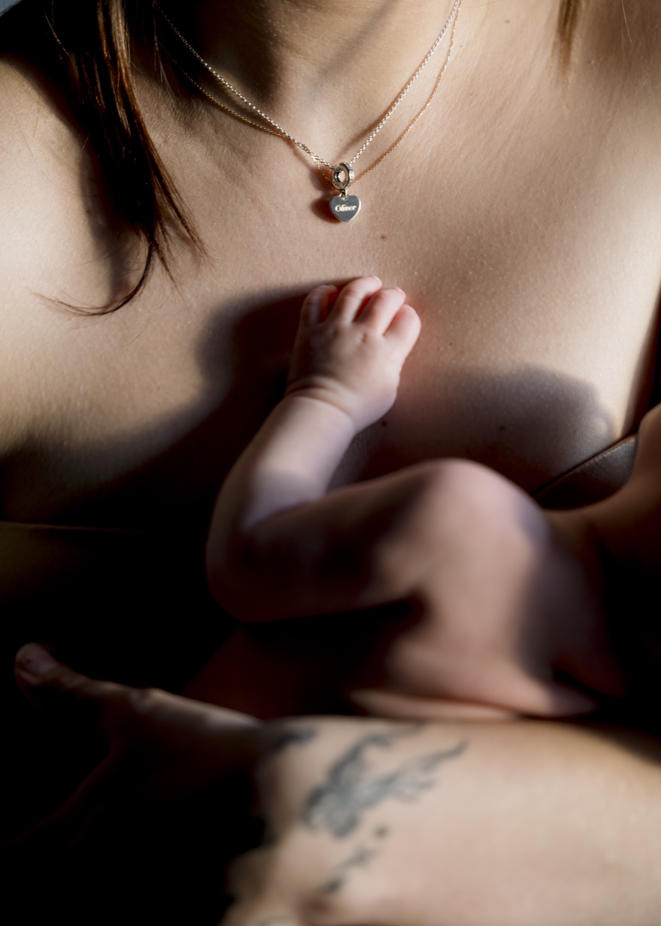 Close detail of a baby resting a small hand against their mother