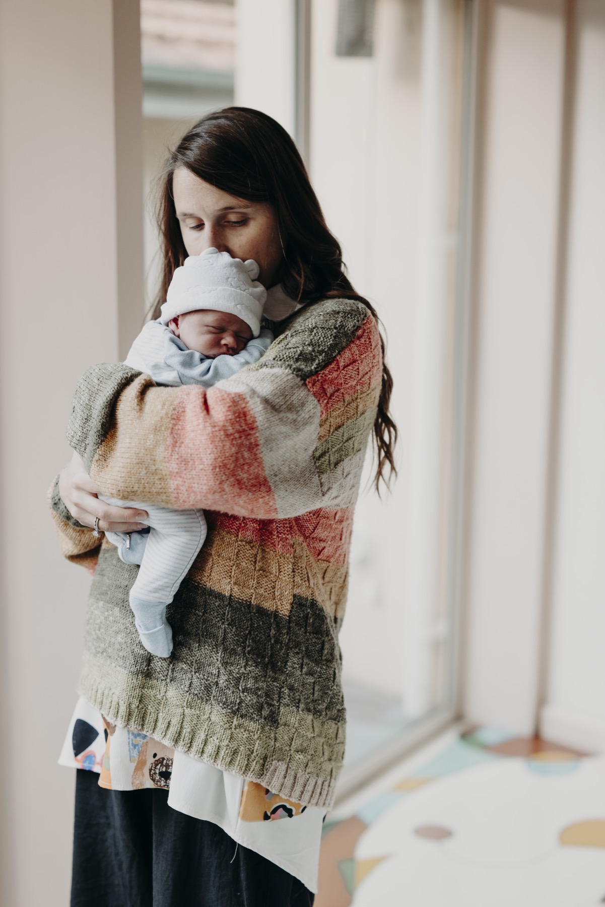 Mother holding her newborn beside a bright window