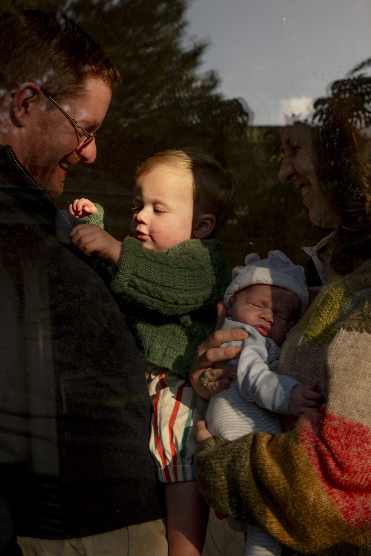 Family holding their children in warm light through a window