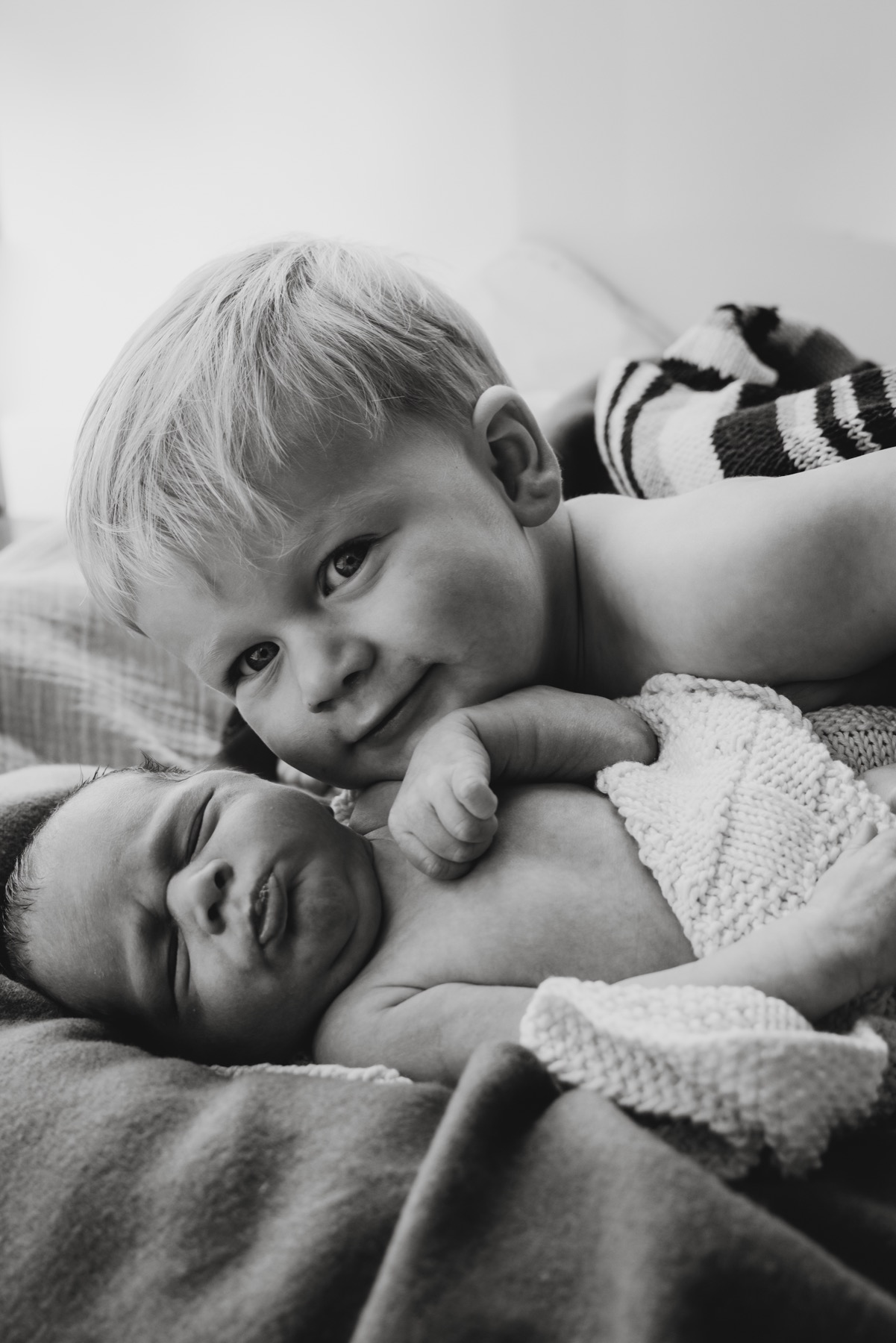 Black and white portrait of a child beside their newborn sibling