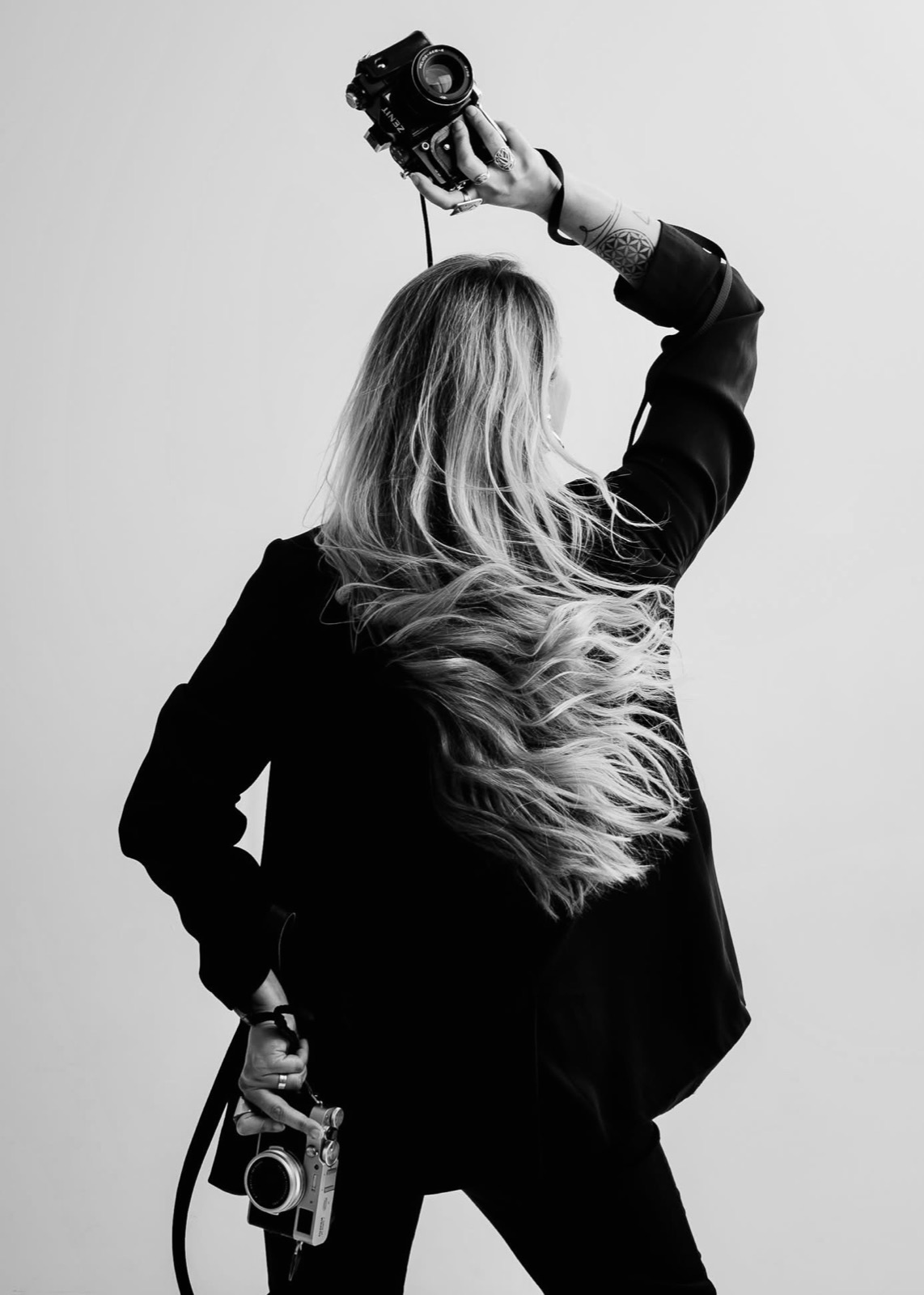 Black and white portrait of Jasna holding two cameras
