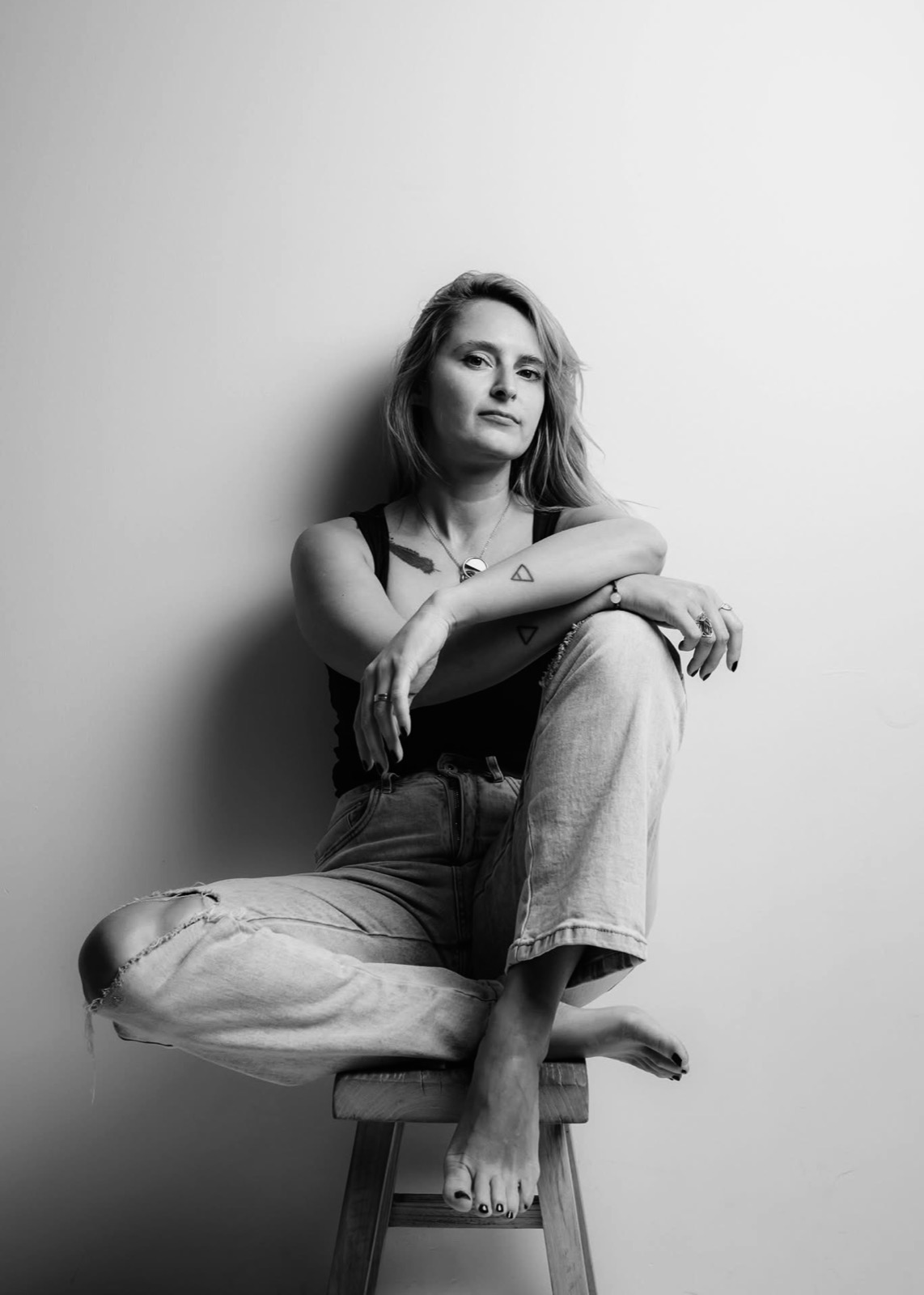 Black and white portrait of Jasna seated on a stool