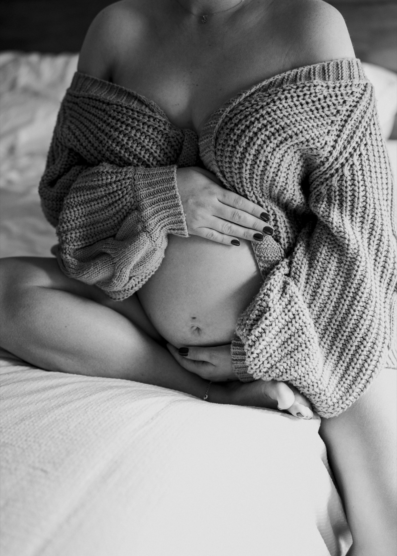 Black and white maternity portrait with hands resting around the bump